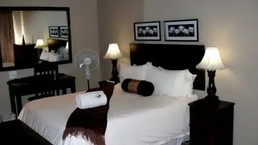 Bedroom with a neatly made bed bedside tables lamps and wall art