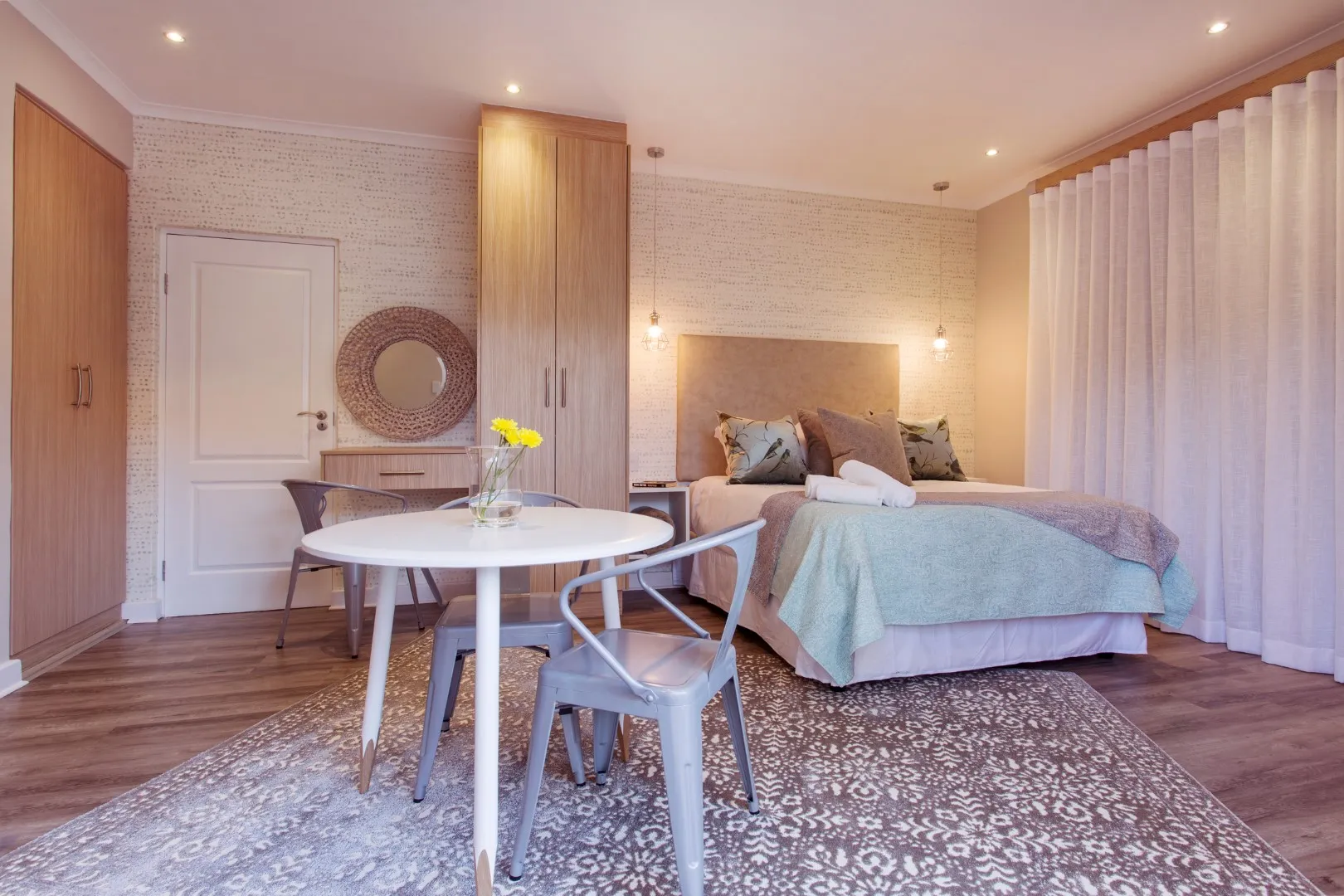 Modern bedroom with bed dining table and chairs on a patterned rug