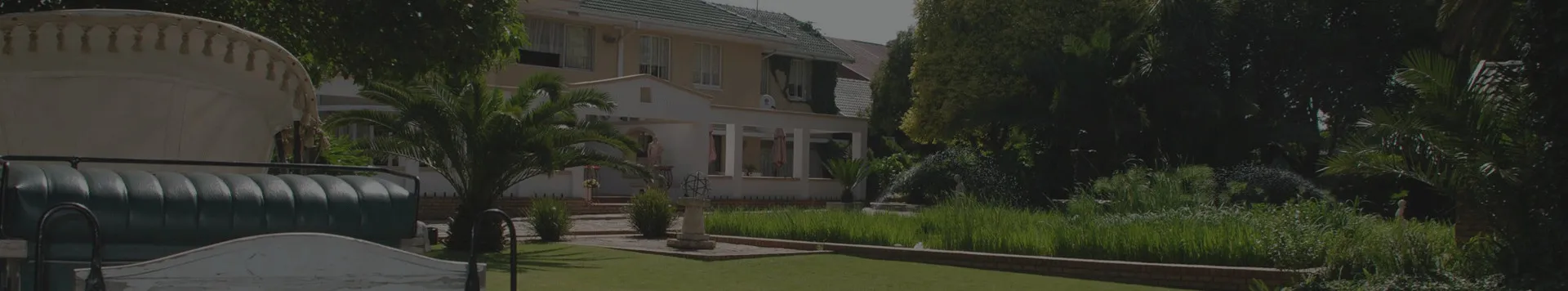 Garden with palm trees flowers and a large building in the background