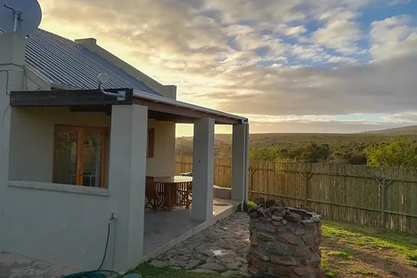 House with a veranda wooden fence and scenic countryside view at sunset