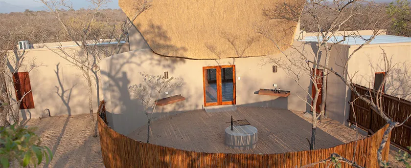 Traditional thatchedroof house with wooden deck and outdoor table in a natural setting