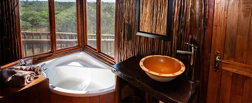 Wooden bathroom with large windows bathtub and stone sink with a view