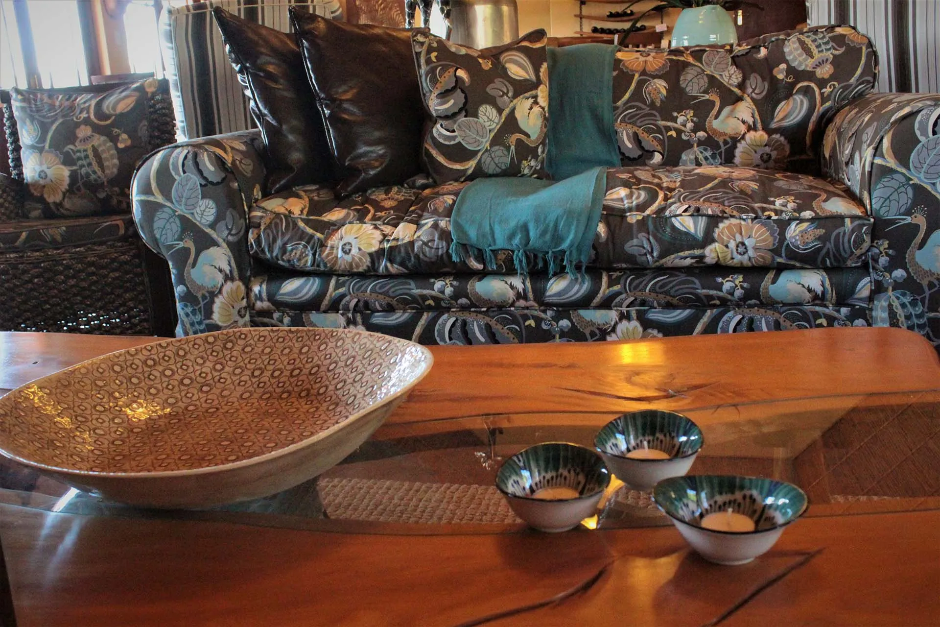 Floralpatterned sofa with teal throw wooden table with bowls in foreground