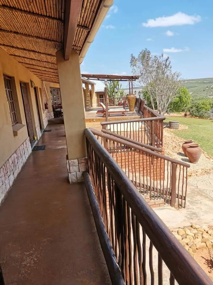 Outdoor walkway with stone and wood railing overlooking a garden and distant hills