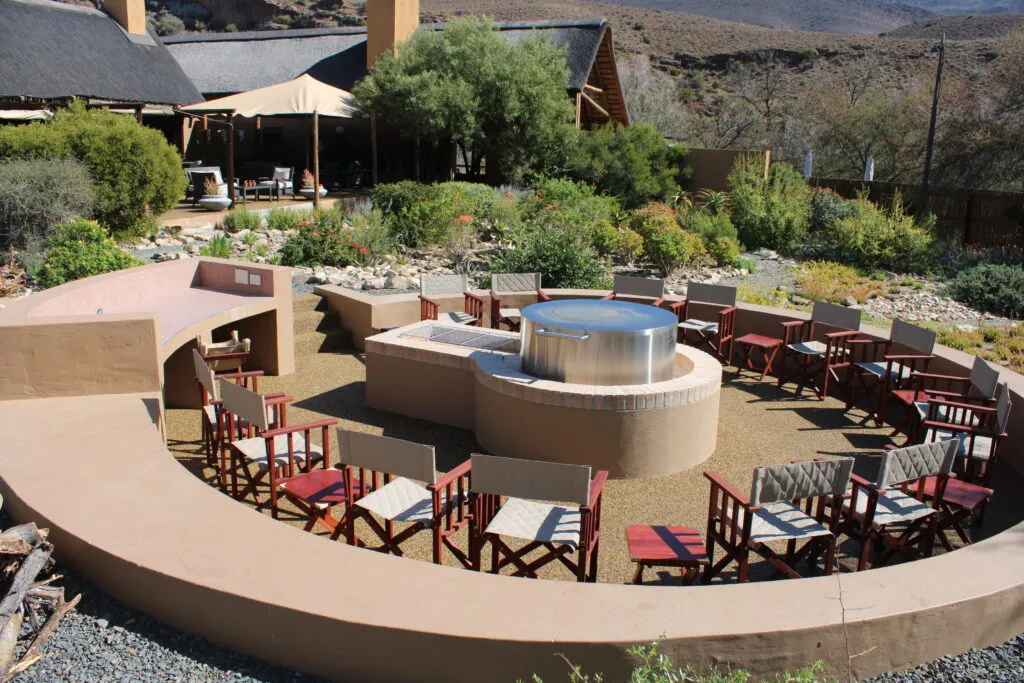 Outdoor seating area with chairs around a fire pit in a garden setting
