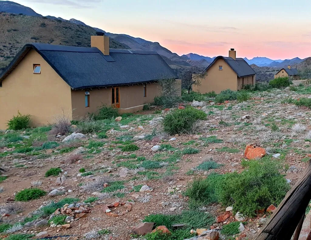 Two yellow cottages in a rocky mountainous landscape at sunset