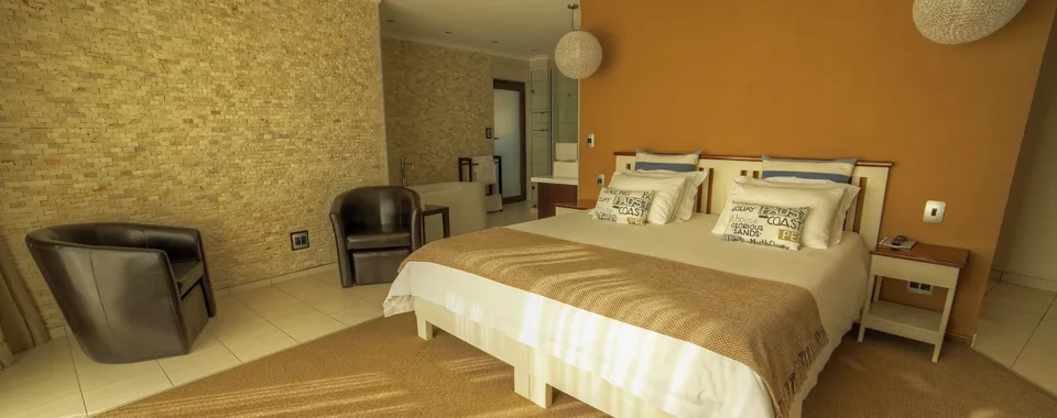 Modern hotel room with a large bed armchair and warm decor