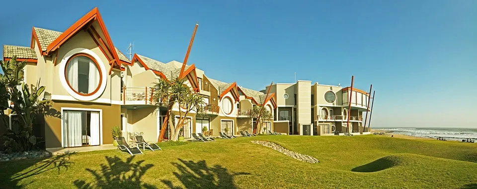 Modern beachfront buildings with unique architecture and green lawn by the ocean