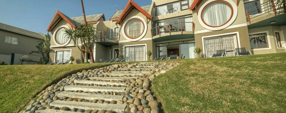 Modern house with large windows and stone pathway leading up a grassy hill