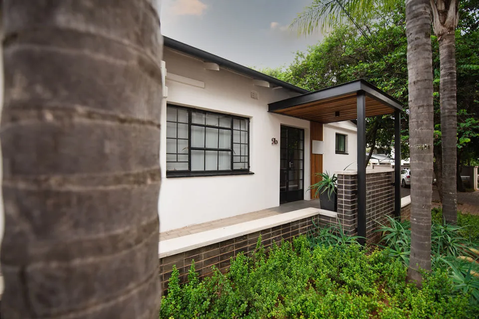 Modern house with large window black door and palm trees in front