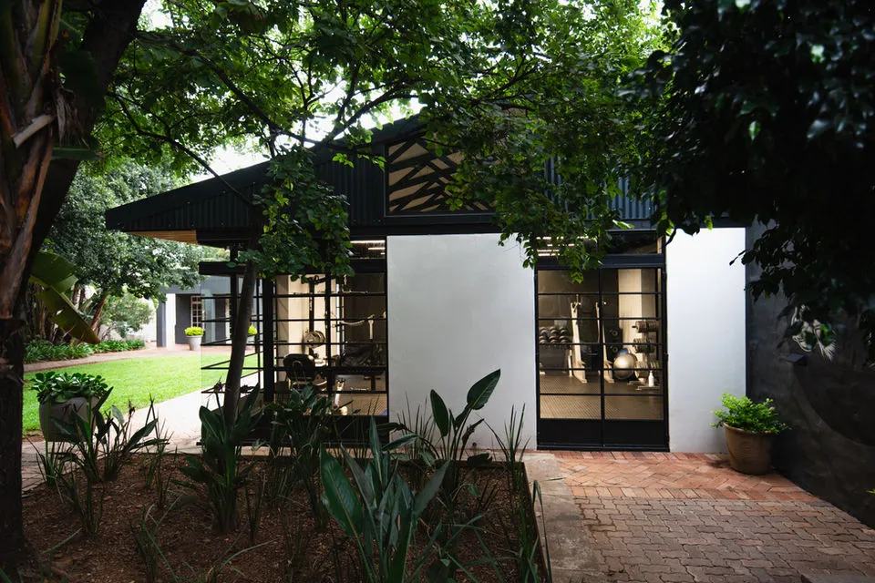 Modern house with large windows surrounded by greenery and a brick pathway
