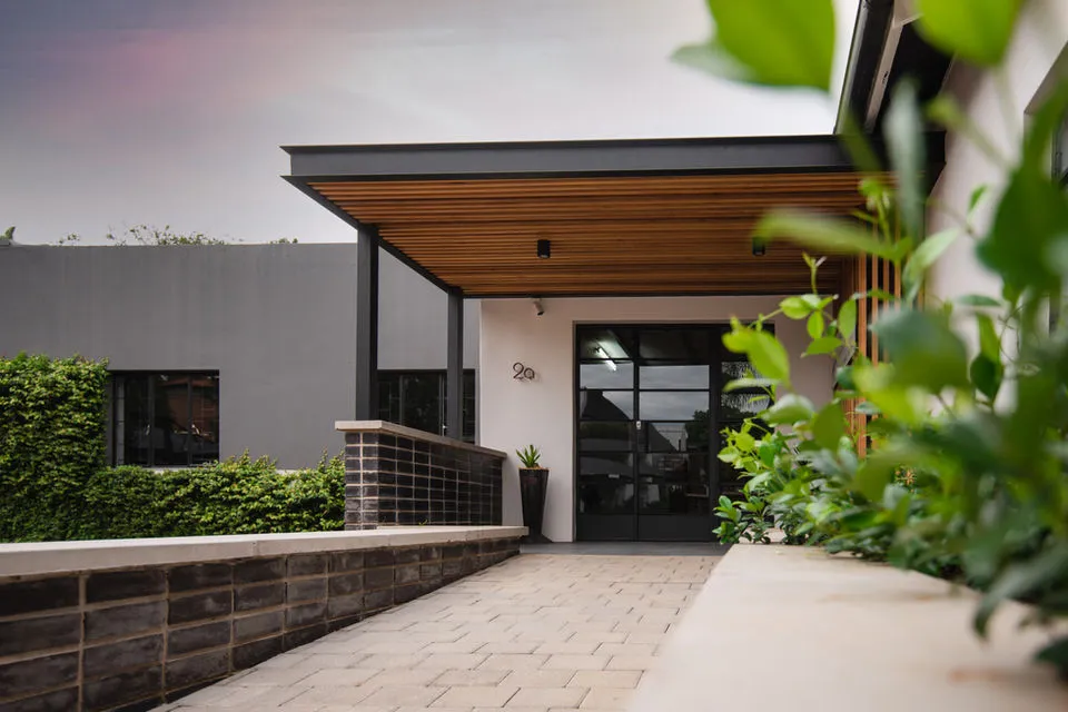 Modern house entrance with covered walkway plants and brick wall