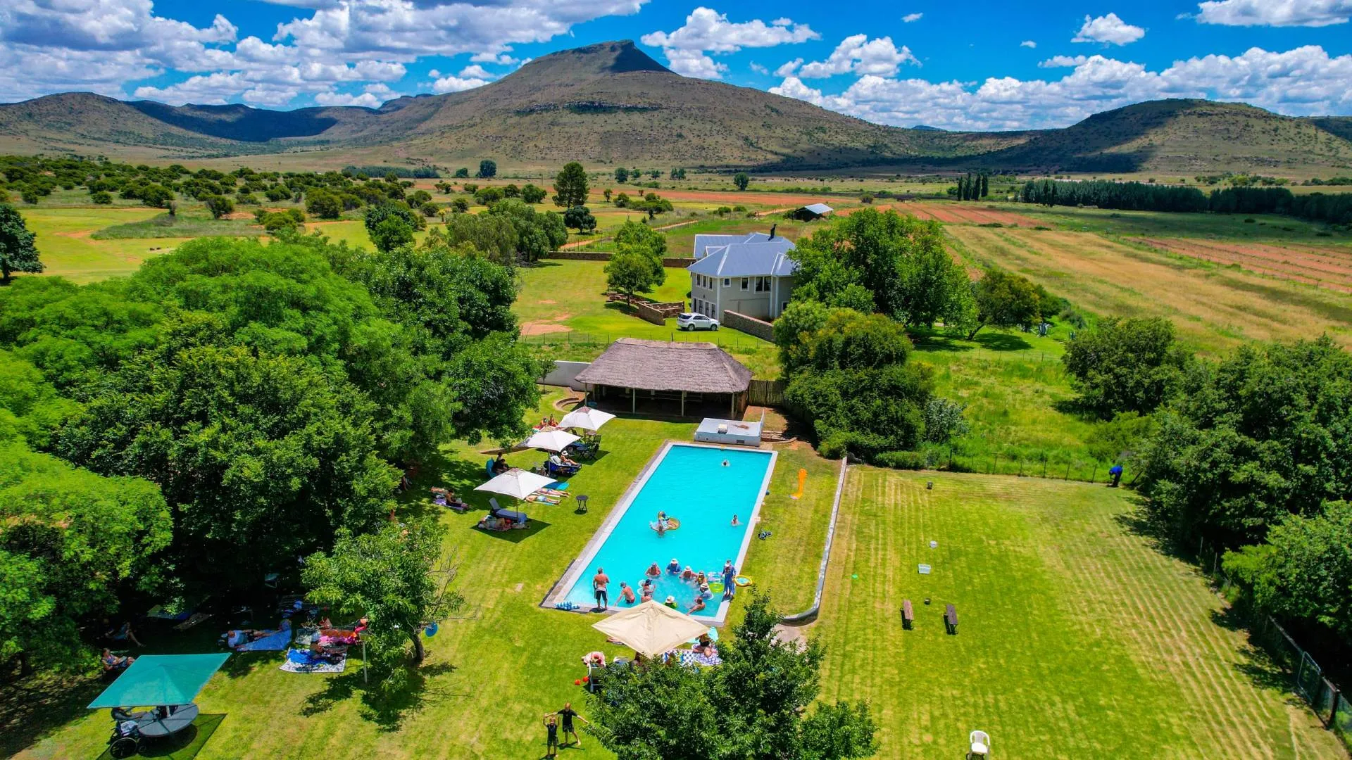 Aerial view of a poolside gathering in a scenic countryside with mountains