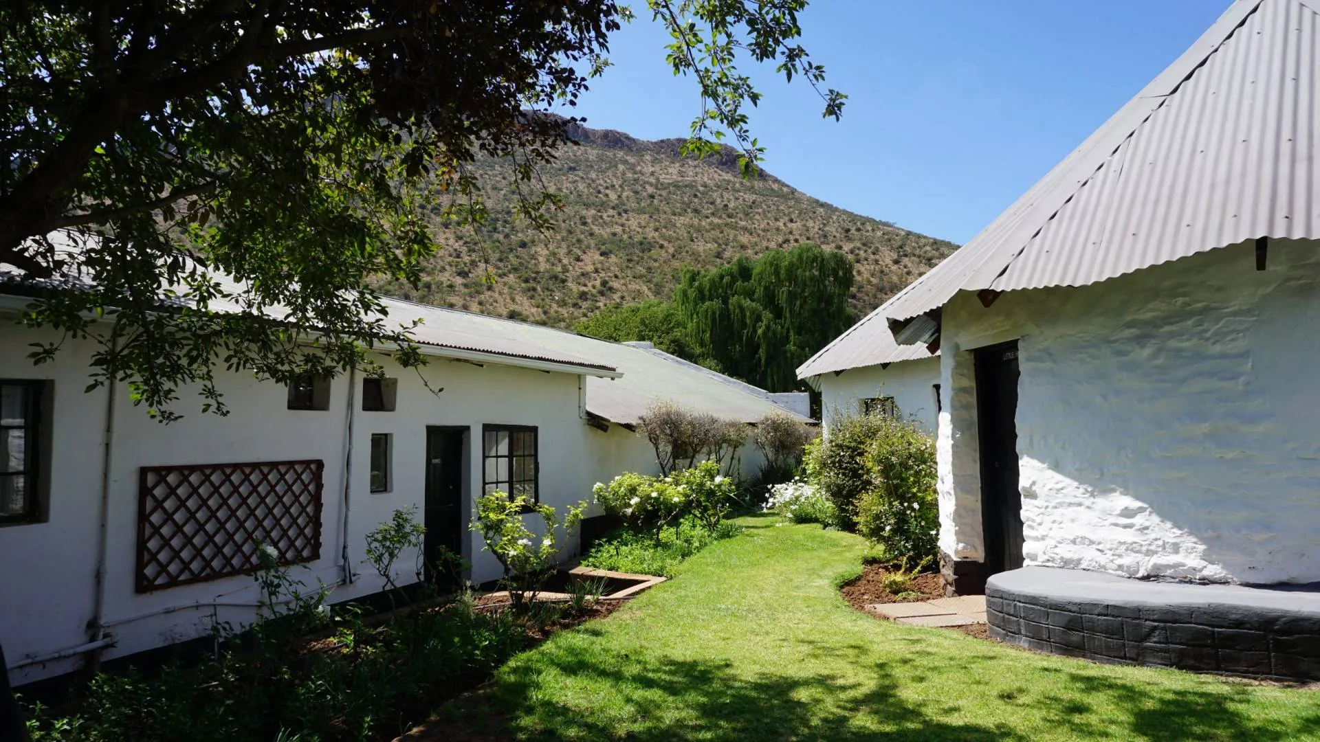 White buildings with a green lawn and trees mountain in the background