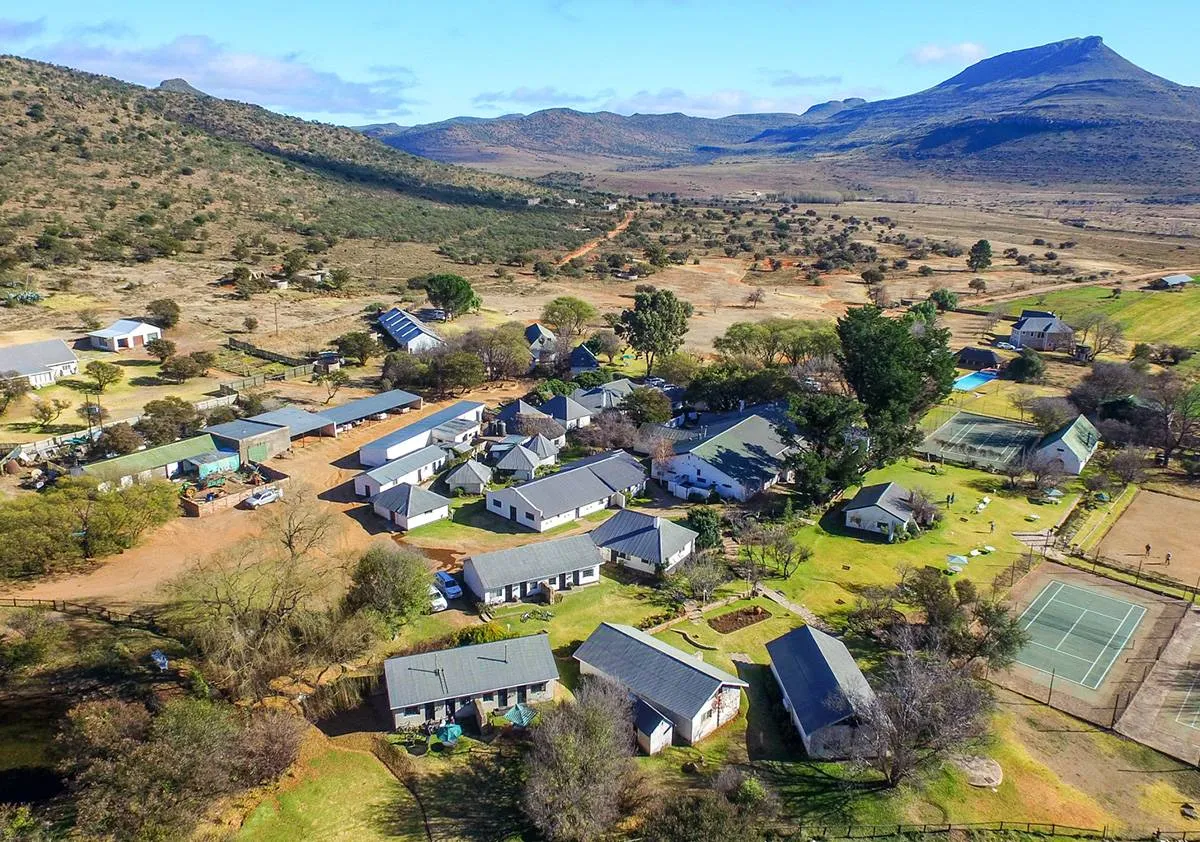 Aerial view of a rural village with buildings trees and mountains in background