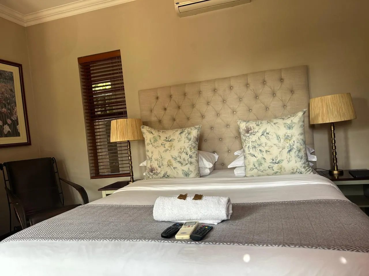 Cozy bedroom with a neatly made bed two lamps and a painting