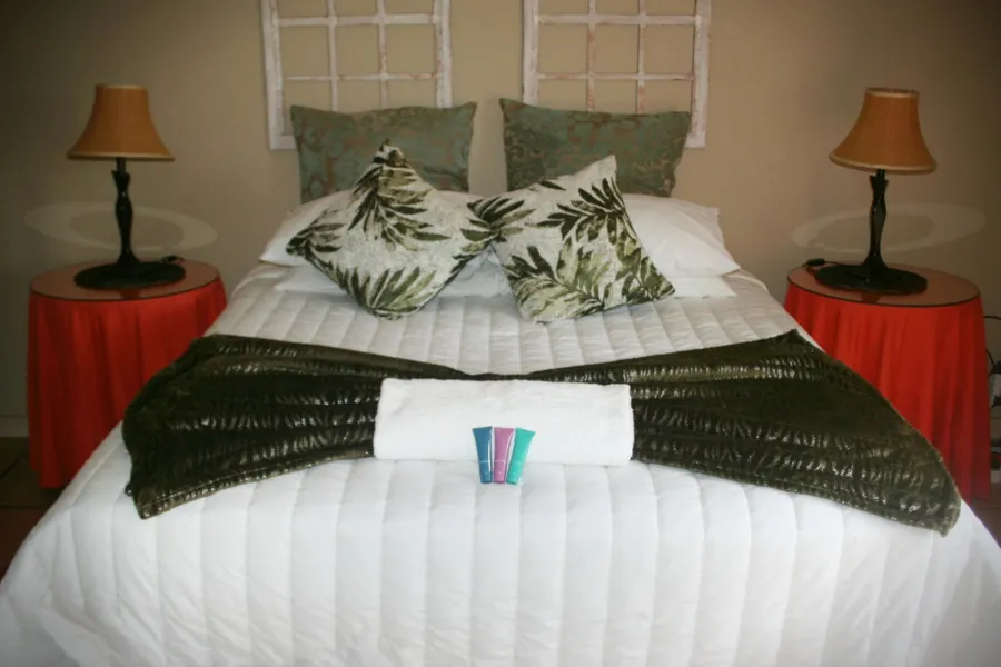Bed with green and white pillows black throw and two bedside tables with lamps