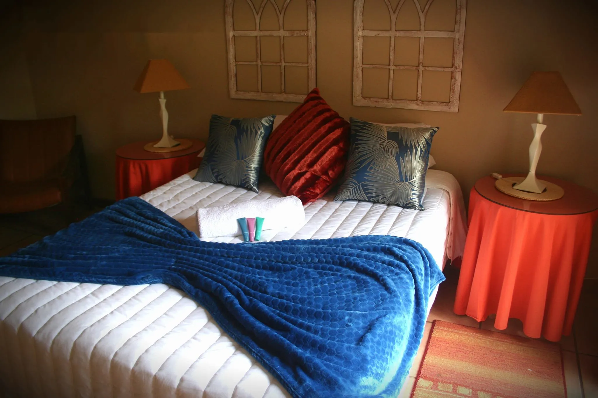 Bedroom with neatly made bed blue throw and bedside tables with lamps