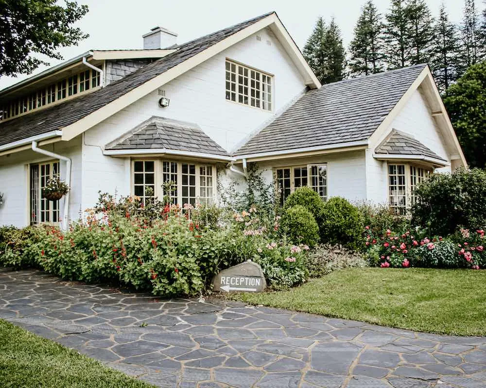 White house with garden and stone pathway leading to a reception sign