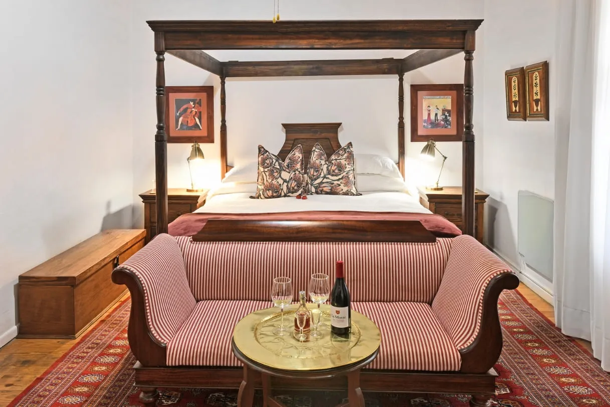 Cozy bedroom with a fourposter bed sofa and wine on a table