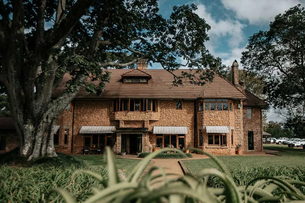 Large brick house with a tiled roof surrounded by greenery and trees