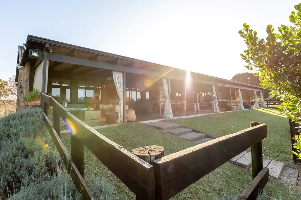 Wooden fence in front of a sunlit outdoor seating area with draped curtains