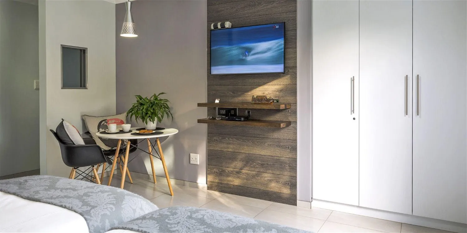 Modern bedroom with TV small table chairs and wardrobe