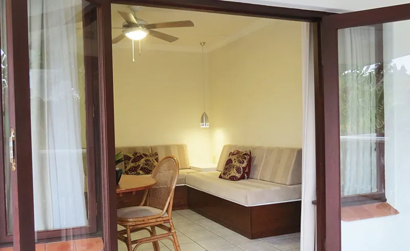 Open door view of a cozy living room with a ceiling fan and sofa