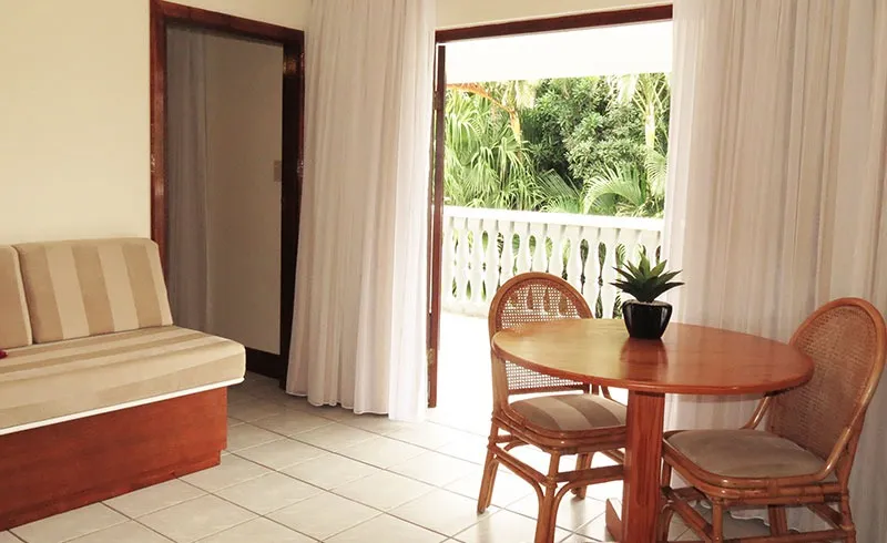 Sofa and dining table in a room with open curtains and a balcony view