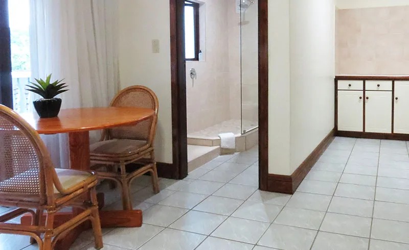 Small dining area with wooden table and chairs next to a bathroom entrance
