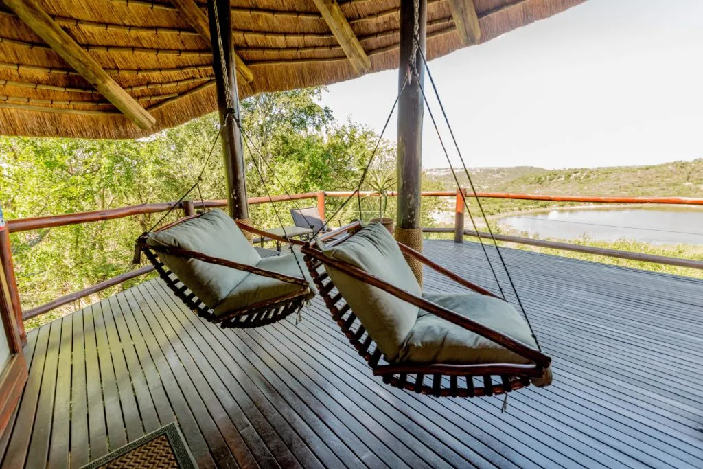 Two hammock chairs on a wooden deck with scenic view of trees and water