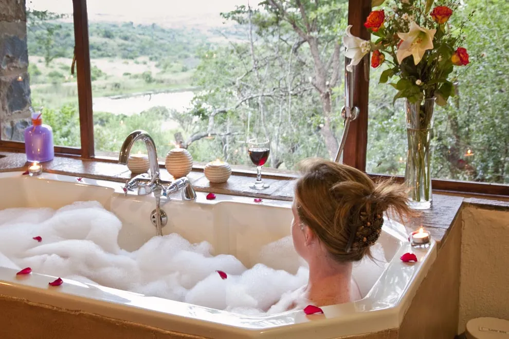 Woman relaxing in a bubble bath with a scenic view and flowers