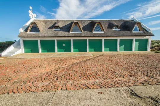 White building with green doors and a brick courtyard under a blue sky