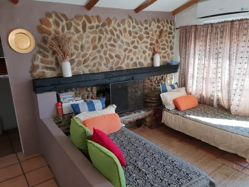 Cozy room with stone fireplace two beds and colorful pillows on a couch