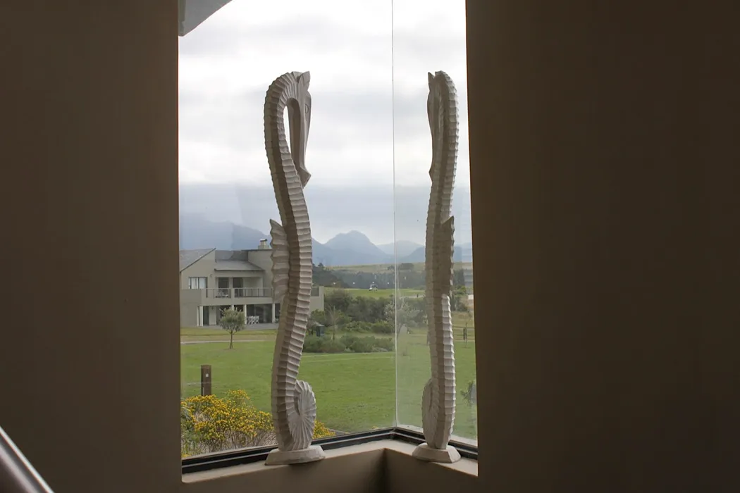 Two seahorse sculptures on a windowsill with a scenic view outside