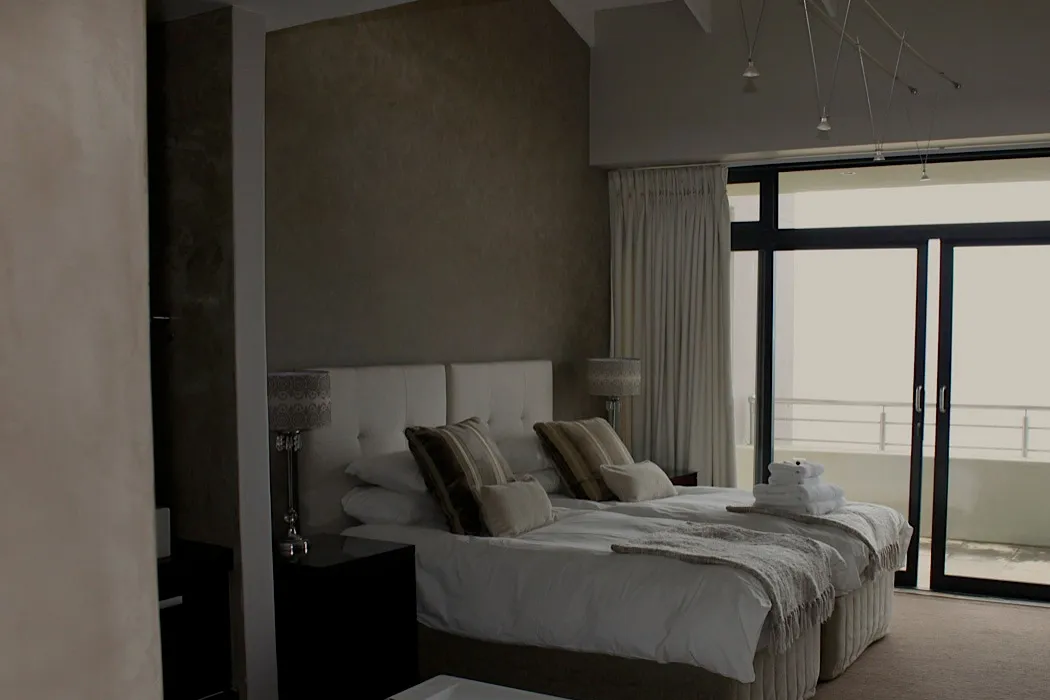 Modern bedroom with two beds large window and neutral decor