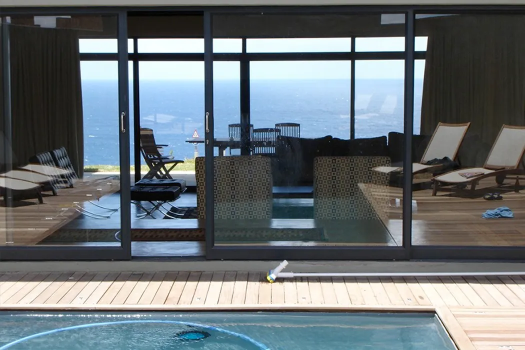 Sliding glass doors with ocean view lounge chairs and pool in foreground