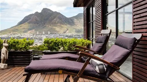 Two lounge chairs on a wooden deck with mountain and city views