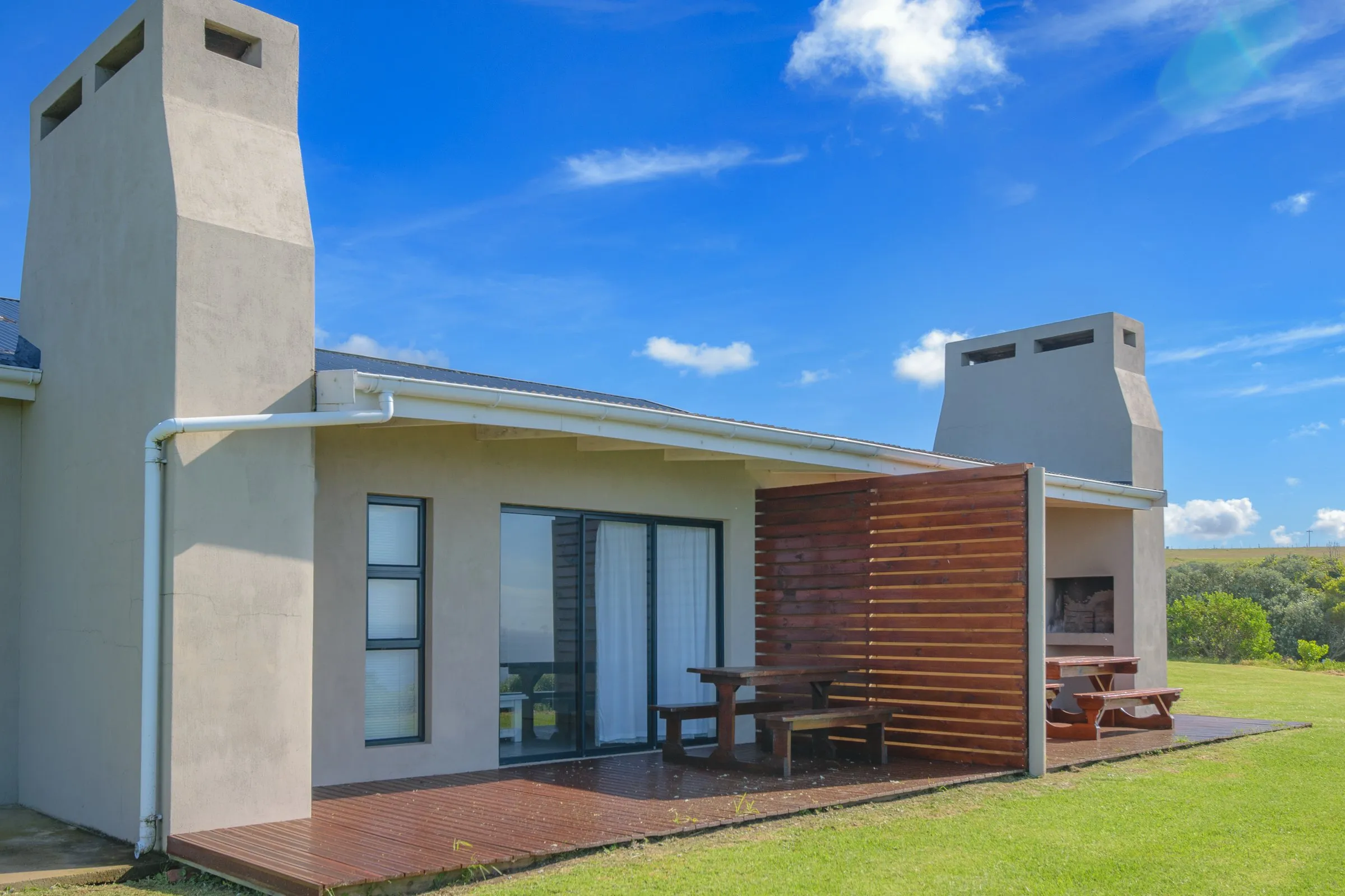 Modern house with wooden deck picnic tables and clear blue sky