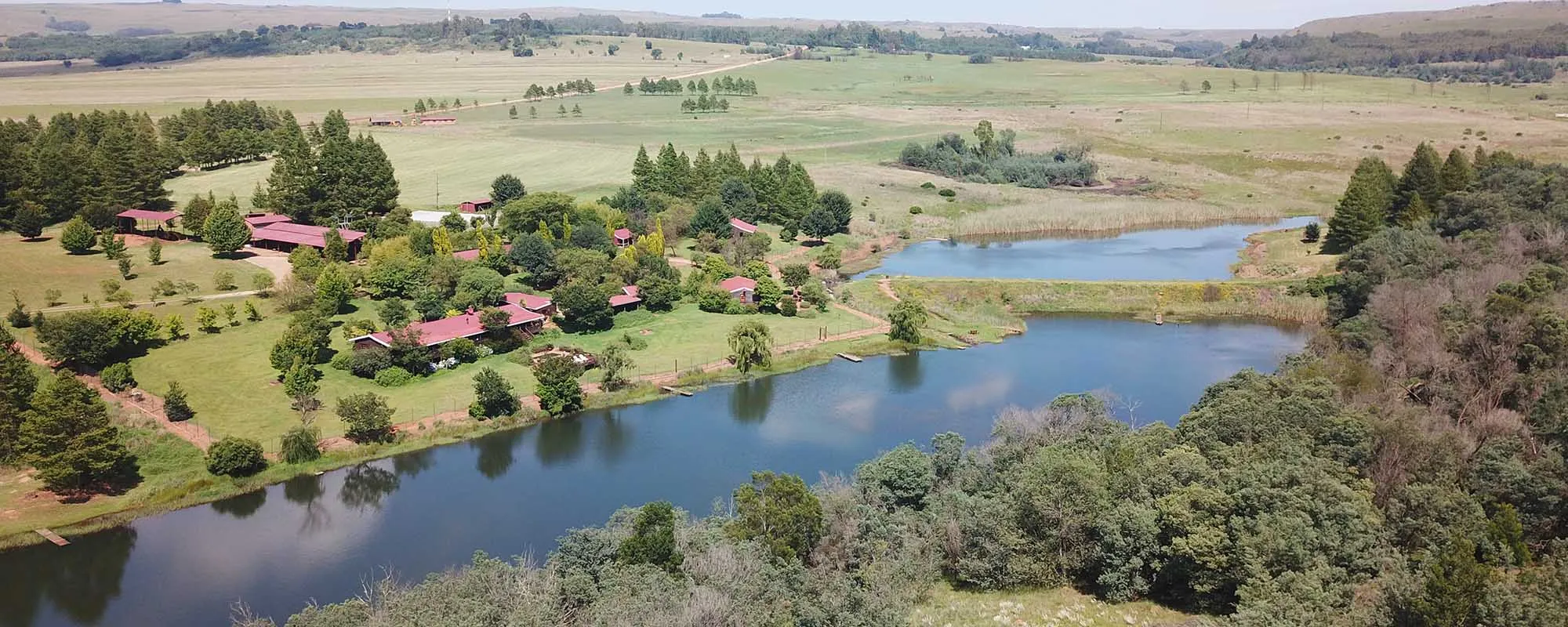 Aerial view of a lakeside settlement with redroofed buildings and surrounding greenery