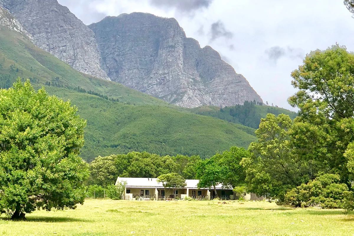 Cottages in a valley with green trees and mountains in the background