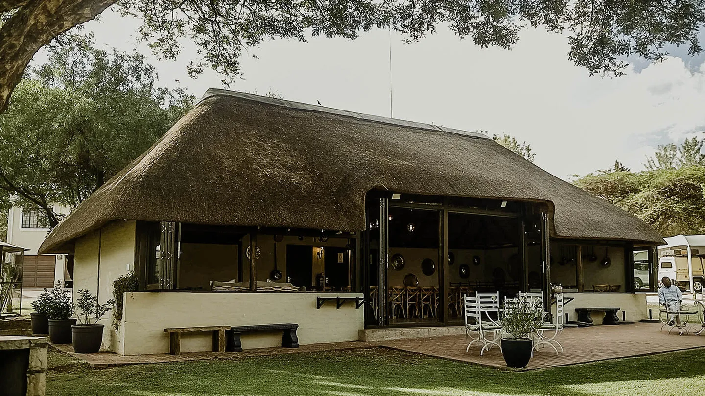 Traditional thatchedroof building with outdoor seating and garden area