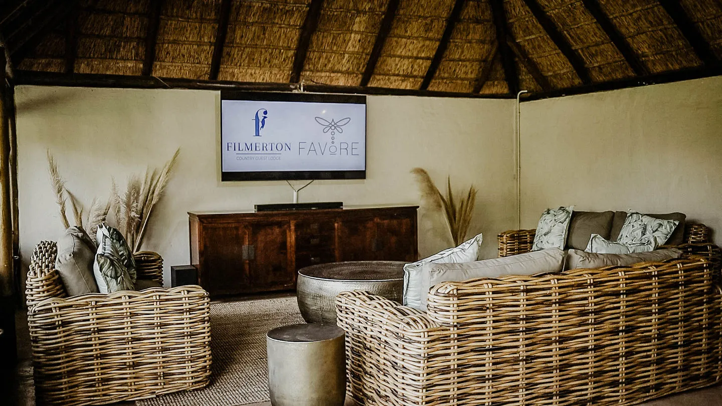 Wicker furniture in a rustic room with a TV and thatched roof