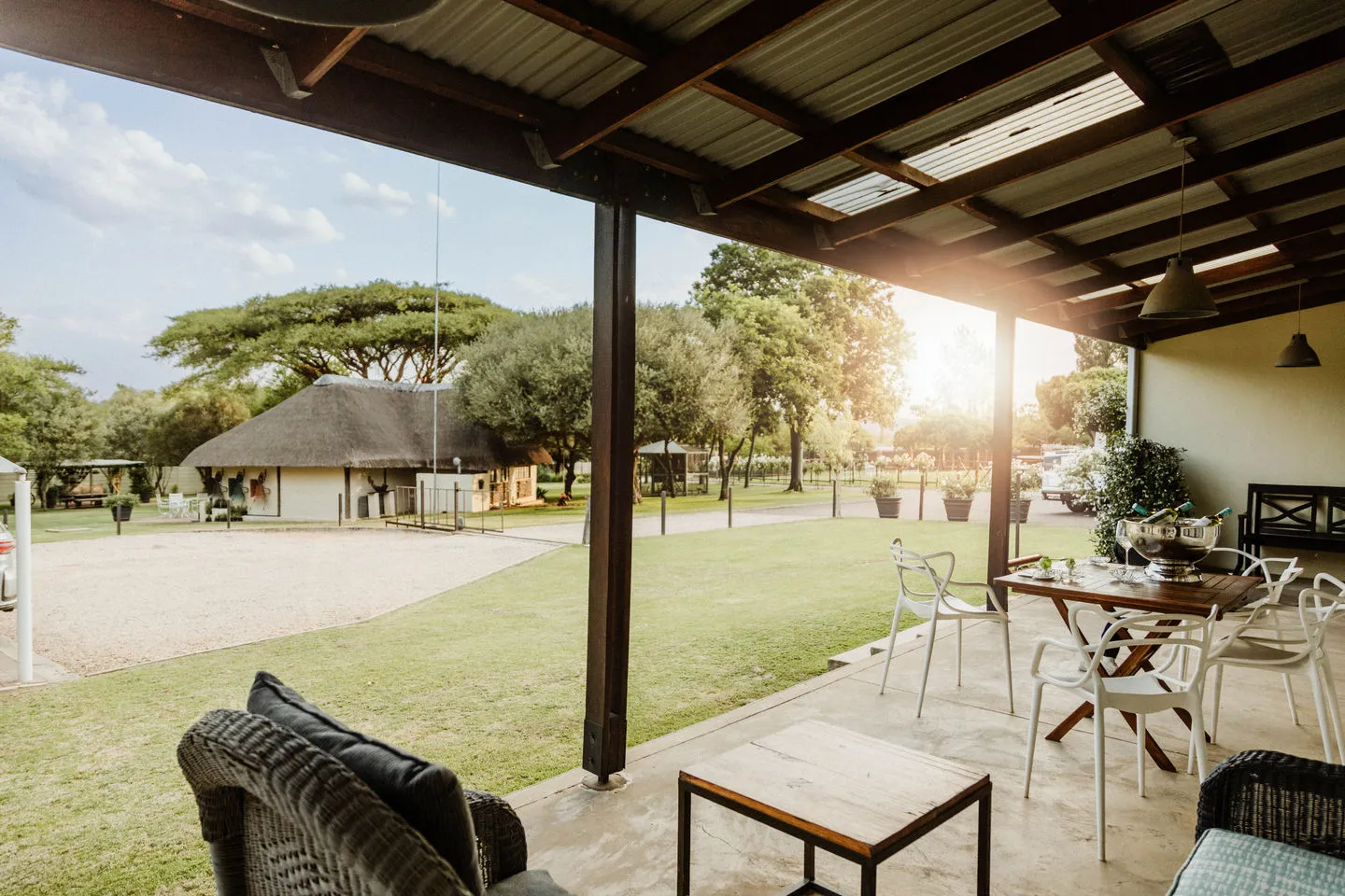 Outdoor seating area with tables and chairs under a covered patio grassy field