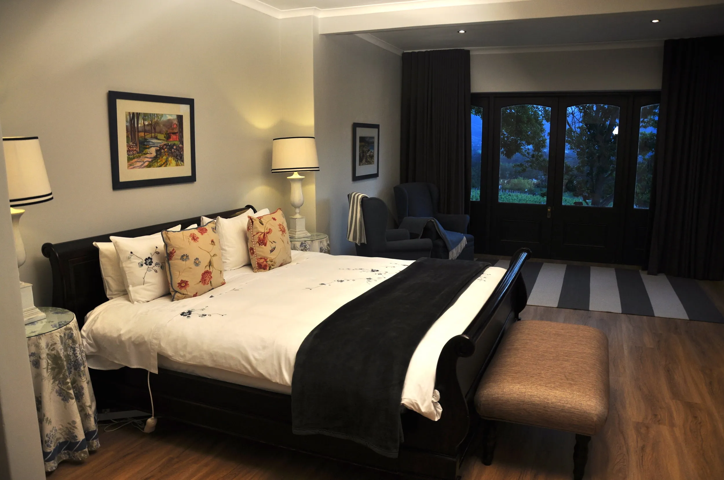 Bedroom with large bed black headboard and view of a garden through glass doors