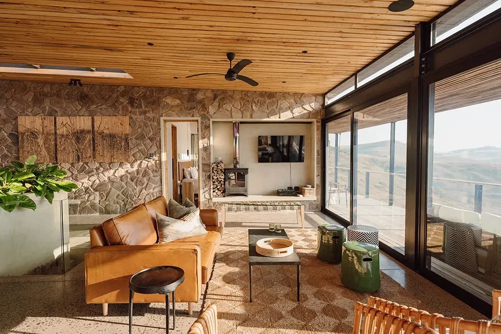 Modern living room with large windows stone wall and mountain view