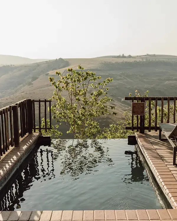 Infinity pool overlooking a scenic valley with trees and hills