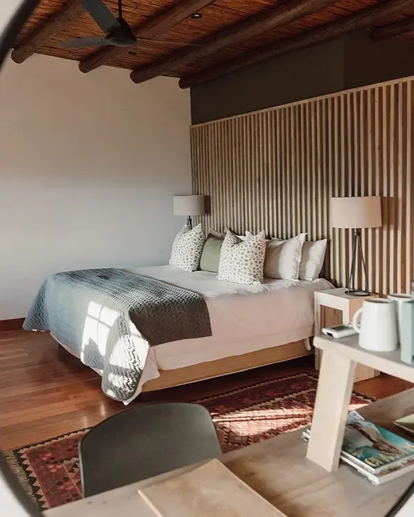Cozy bedroom with wooden ceiling large bed and wooden slat wall