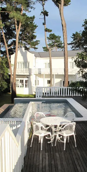 White house with pool deck chairs and trees in the background