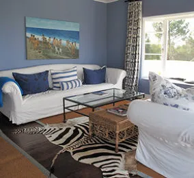 Blue living room with white furniture zebra rug and beach painting